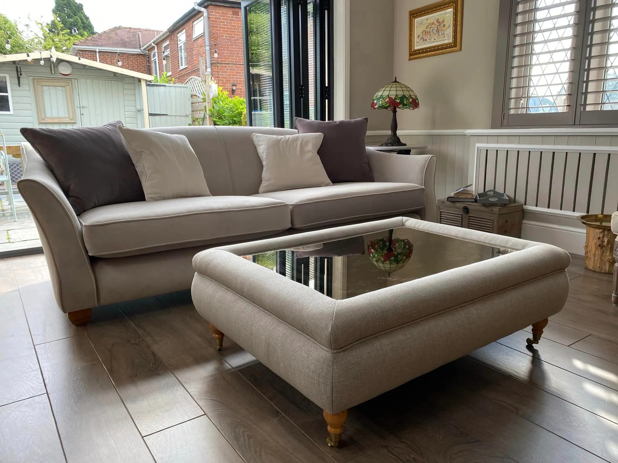 A modern living room showcasing a recently upholstered sofa and an elegant glass top table for a welcoming atmosphere.