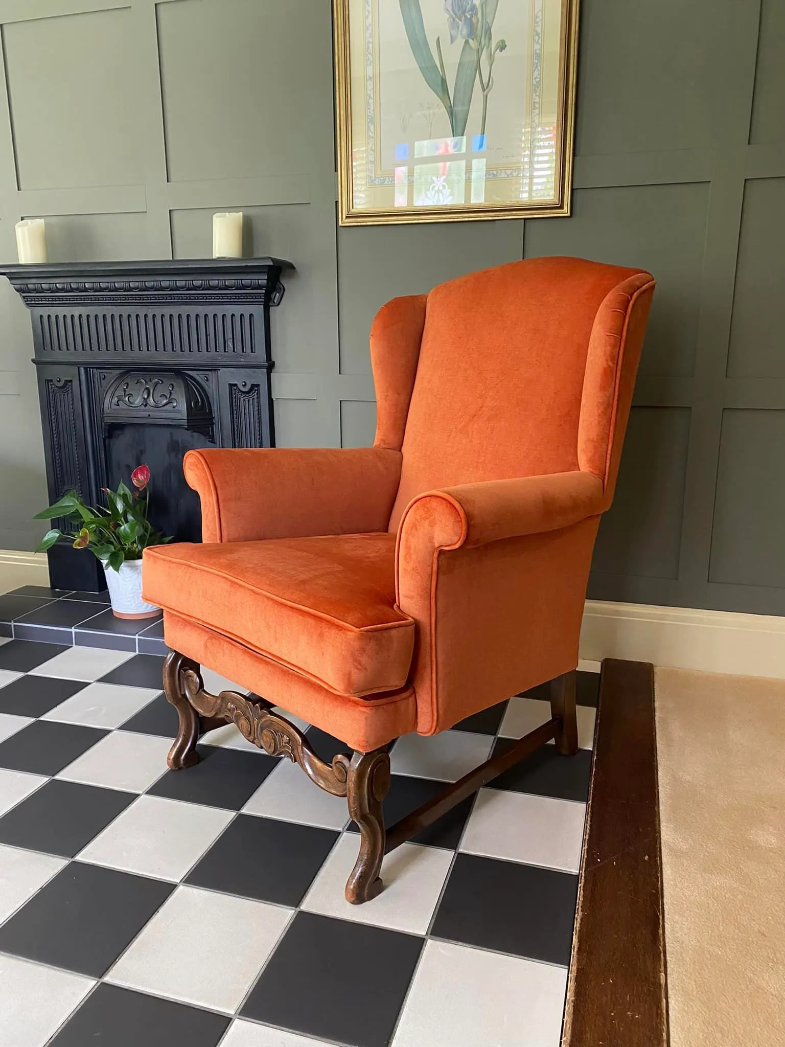 An orange chair located in front of a fireplace, offering a bright focal point in a warm, inviting space.