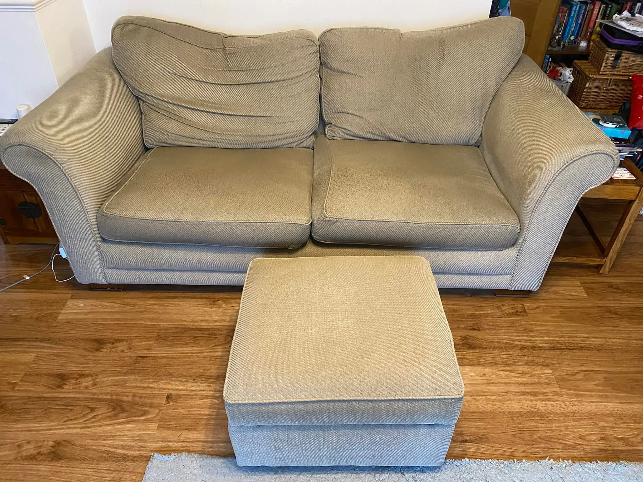 A old couch and matching ottoman positioned on a sleek wooden floor.